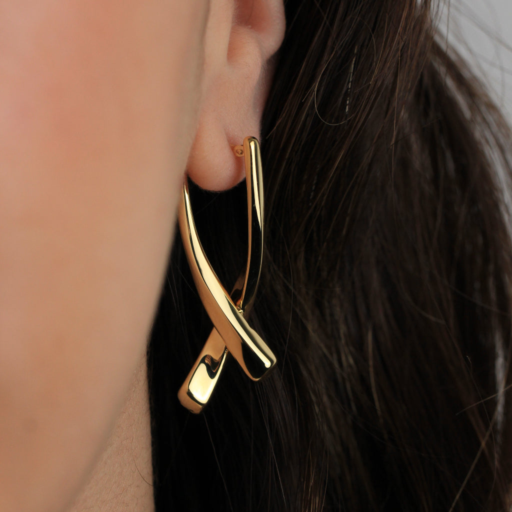 Pendientes realizados en oro amarillo de 18 quilates en forma de doble tubo cruzado en X.