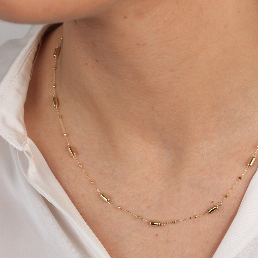 Gargantilla en oro amarillo de 18 quilates con motivos de tubos y bolas pequeñas.