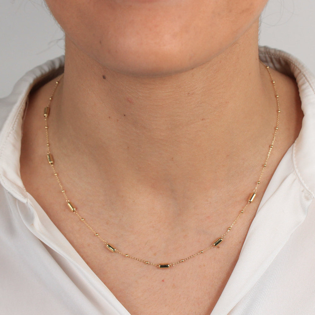 Gargantilla en oro amarillo de 18 quilates con motivos de tubos y bolas pequeñas.