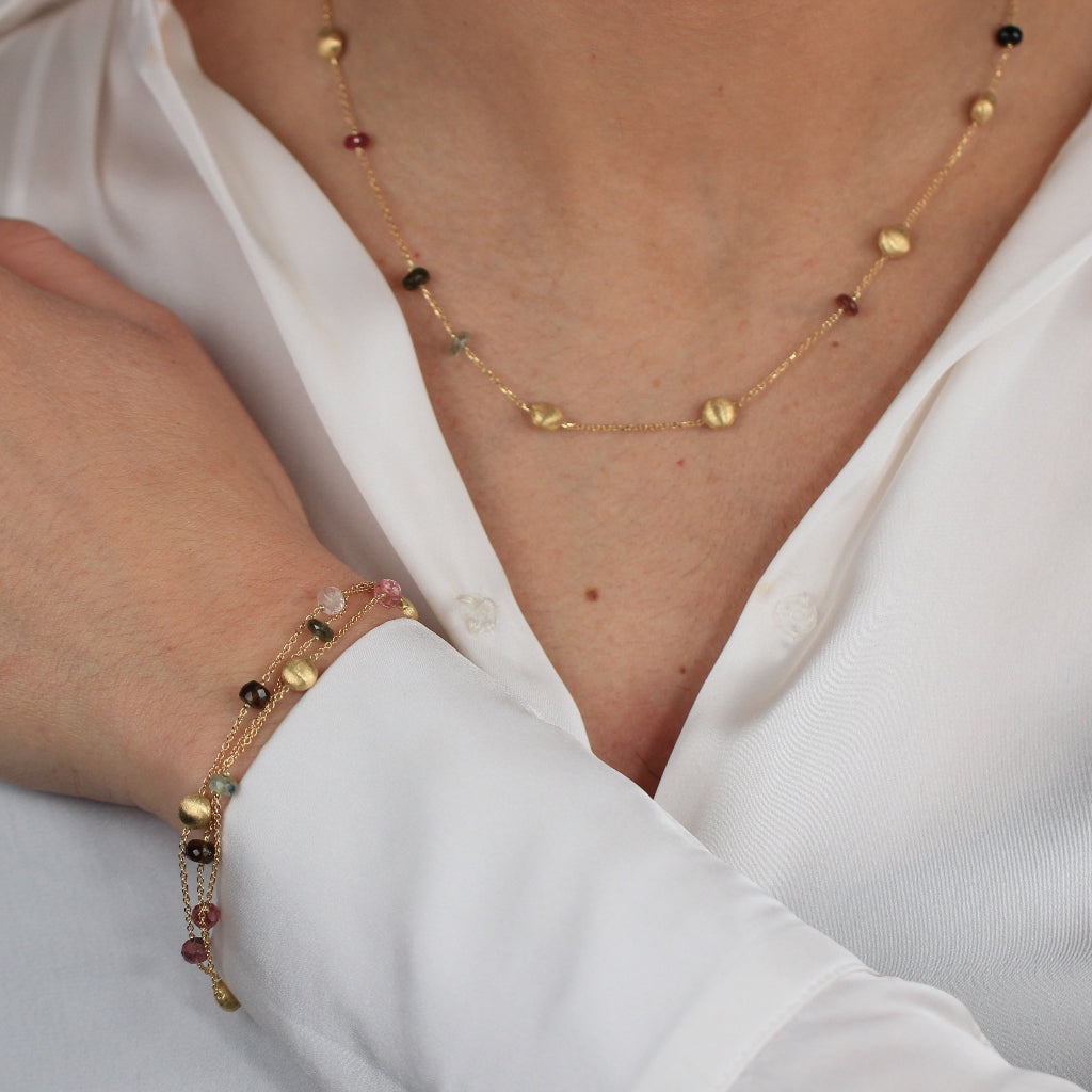 Pulsera realizada en oro amarillo de 18 quilates con tres cadenas, motivos circulares mate, turmalinas y cuarzo fumé.