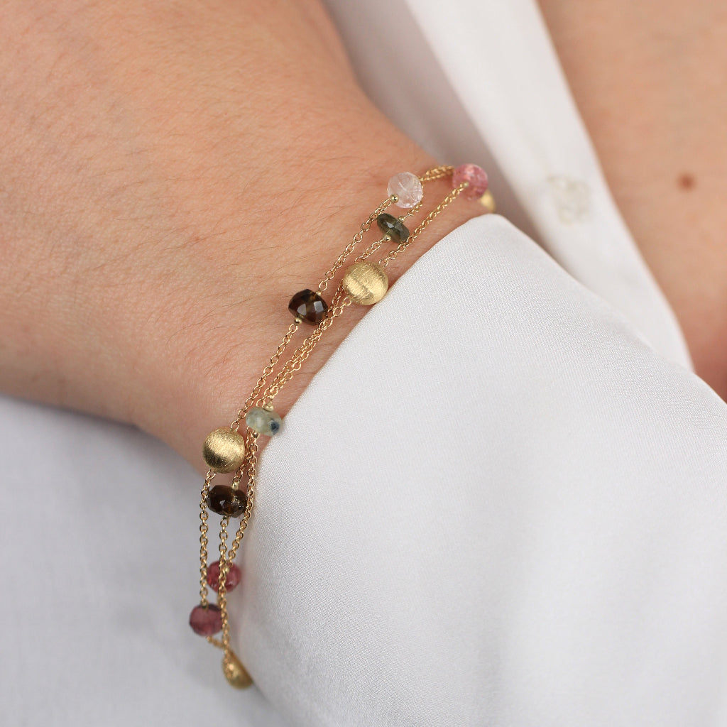 Pulsera realizada en oro amarillo de 18 quilates con tres cadenas, motivos circulares mate, turmalinas y cuarzo fumé.