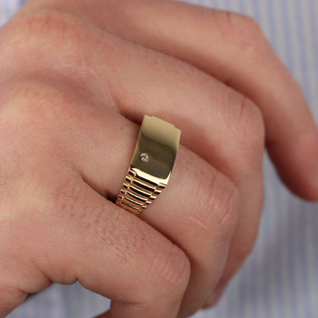 Sello rectángular con una circonita y brazo texturizado. Realizado en oro amarillo de 18 quilates.