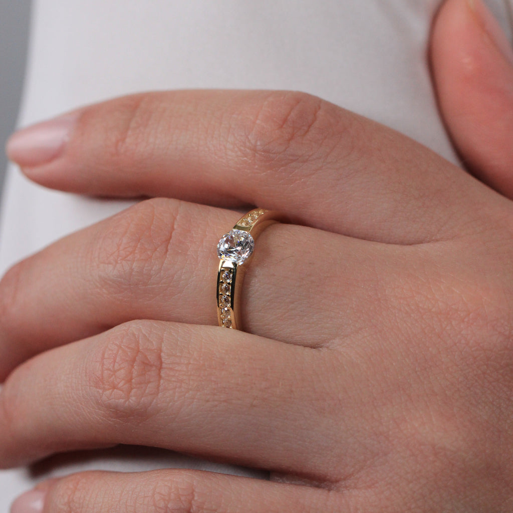 Sortija realizada en oro amarillo de 18 quilates con un solitario de circonita y circonitas en los brazos.