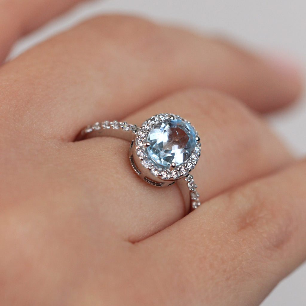 Sortija realizada en oro blanco de 18 quilates con una aguamarina central, orla de circonitas y circonitas en el brazo.