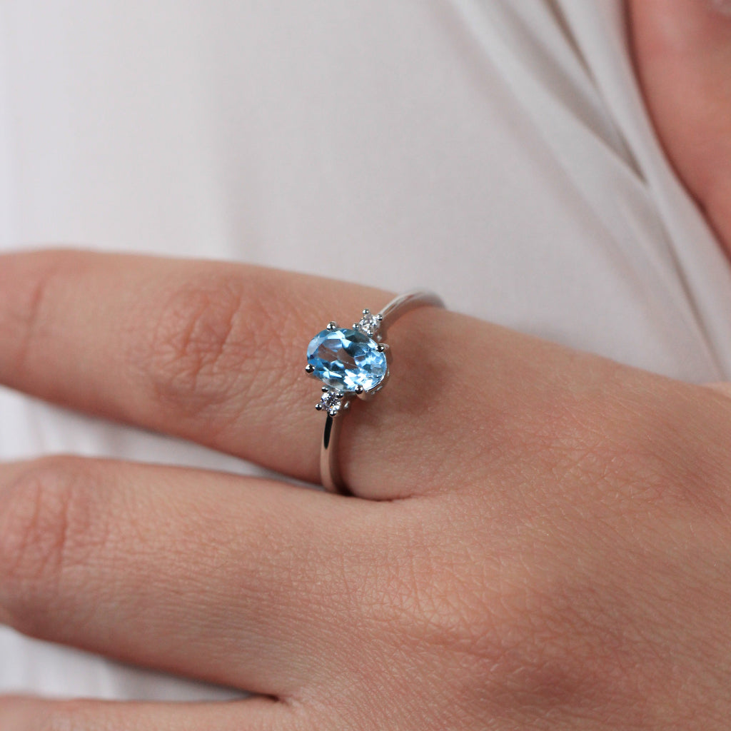 Sortija realizada en oro blanco de 18 quilates con un topacio azul central y dos circonitas.