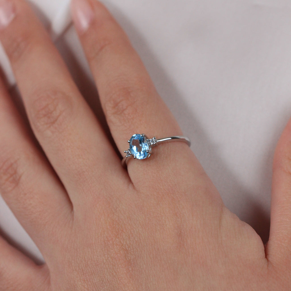 Sortija realizada en oro blanco de 18 quilates con un topacio azul central y dos circonitas.