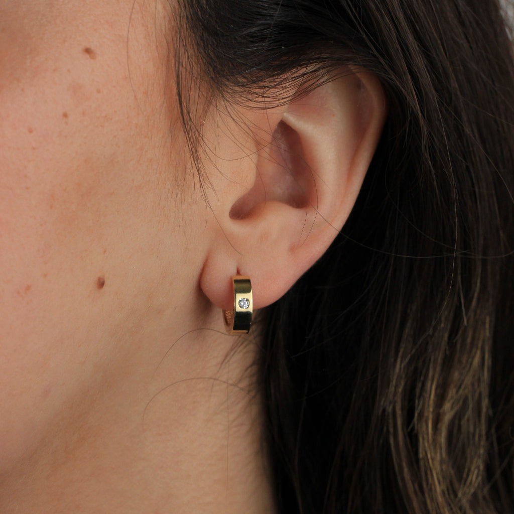 Pendientes de aro en oro amarillo de 18 quilates liso con forma aplanada y una circonita.