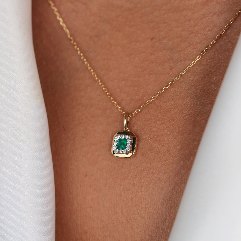 Collar de oro amarillo de 18k con una esmeralda central y orla de diamantes