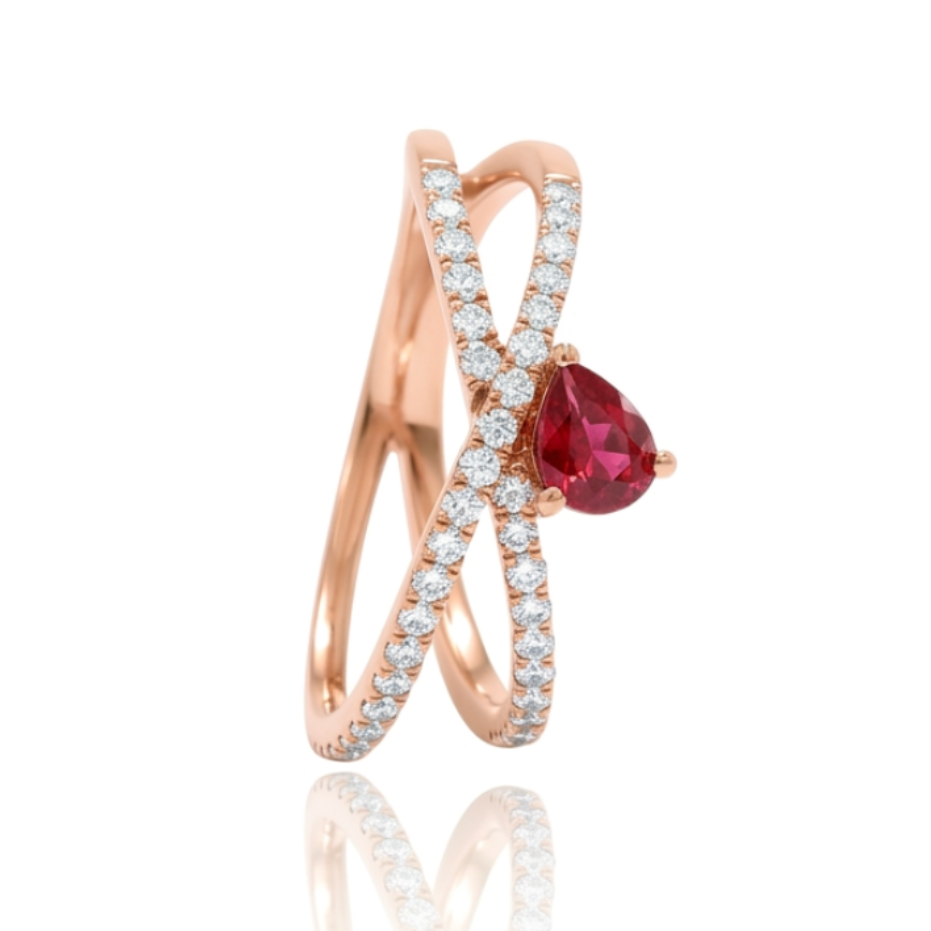 Sortija realizada en oro rosa de 18 K, con un brazo doble cruzado, pavonado con diamantes talla brillante y con un rubí en talla pera engastado en garras.
