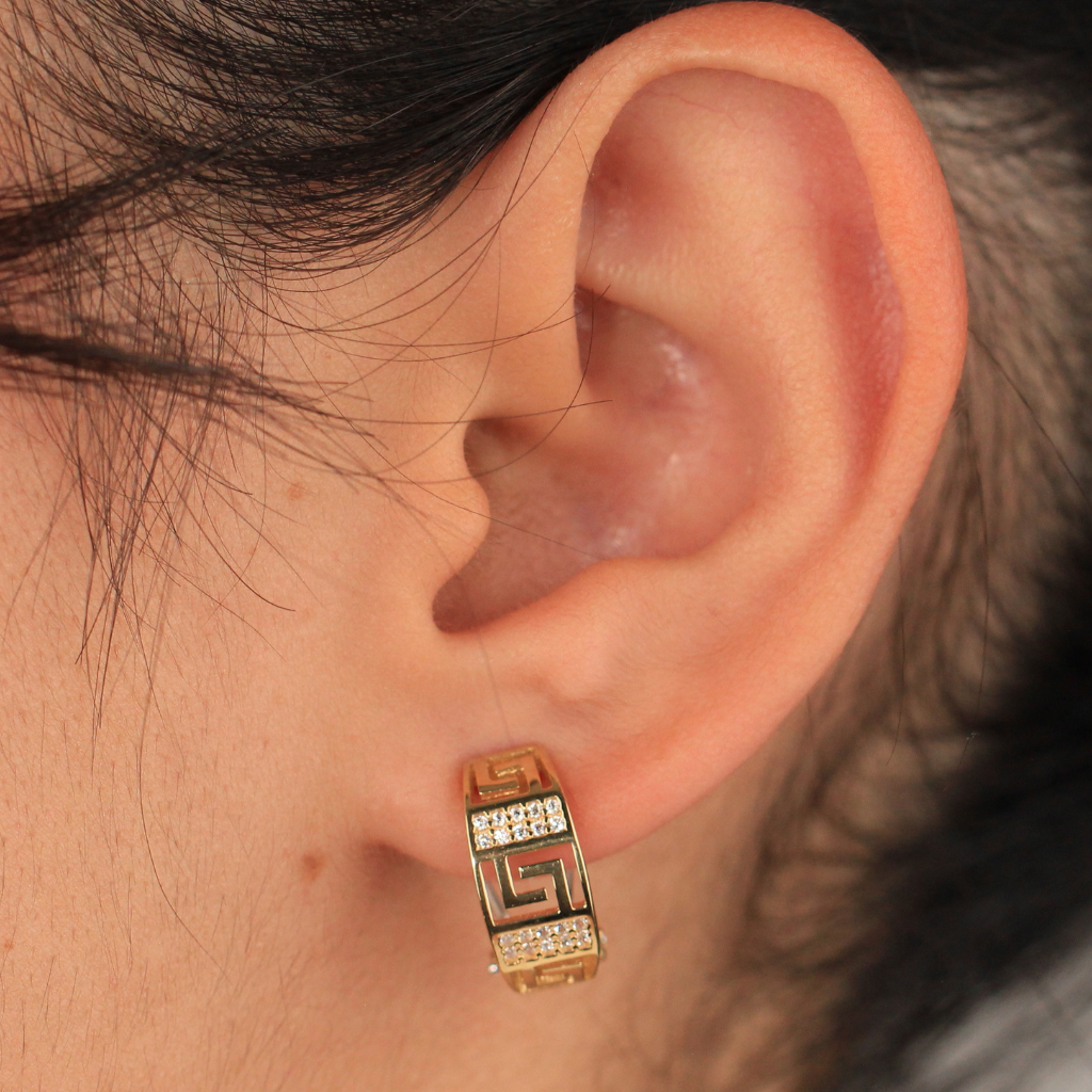 Pendientes realizados en oro amarillo de 18 quilates tipo aro con motivo greca y circonitas.