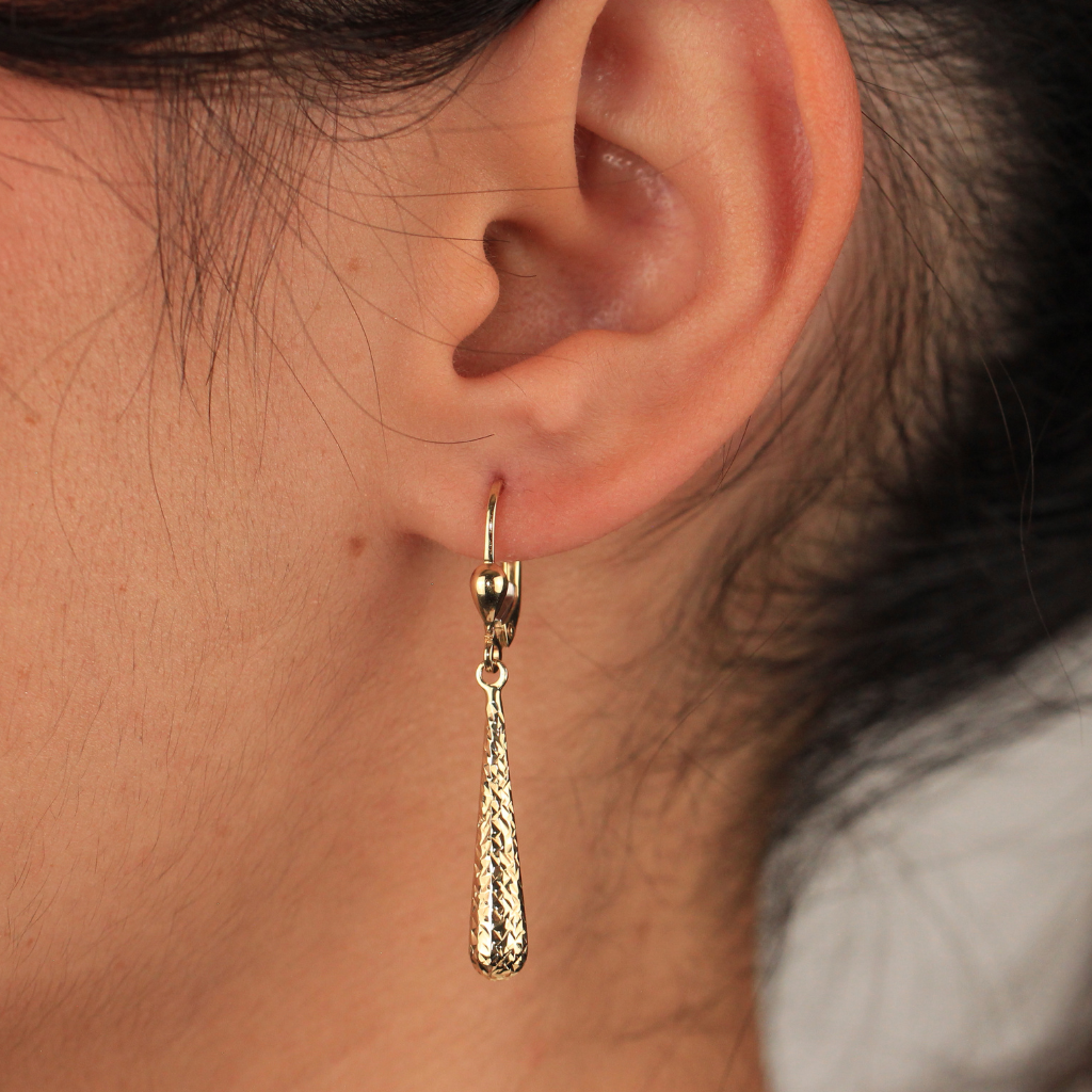 Pendientes realizados en oro amarillo de 18 quilates con colgante en forma de lágrima alargada y acabado diamantado.
