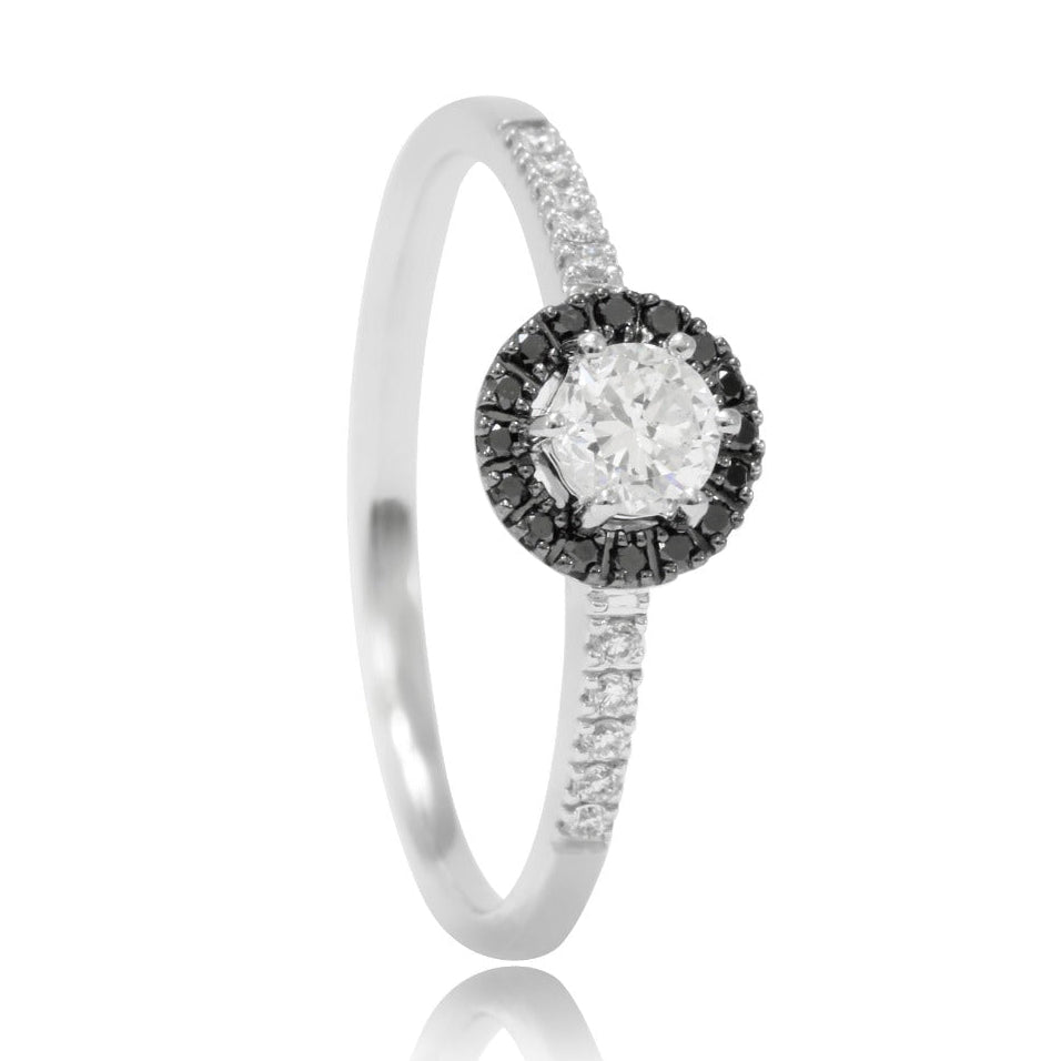 Sortija solitario de oro blanco de 18 quilates con brazos cuajados en diamantes y como motivo principal un diamante talla brillante con una orla de brillantes de color negro. Joyería Pamplona