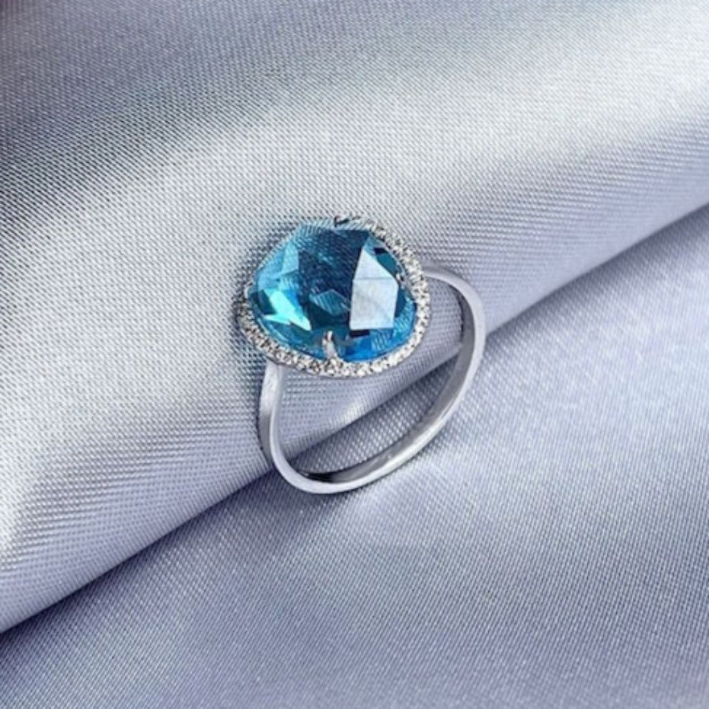 Sortija en oro blanco de 18 quilates, con un topacio azul facetado y una orla de 38 diamantes. Joyería Pamplona.