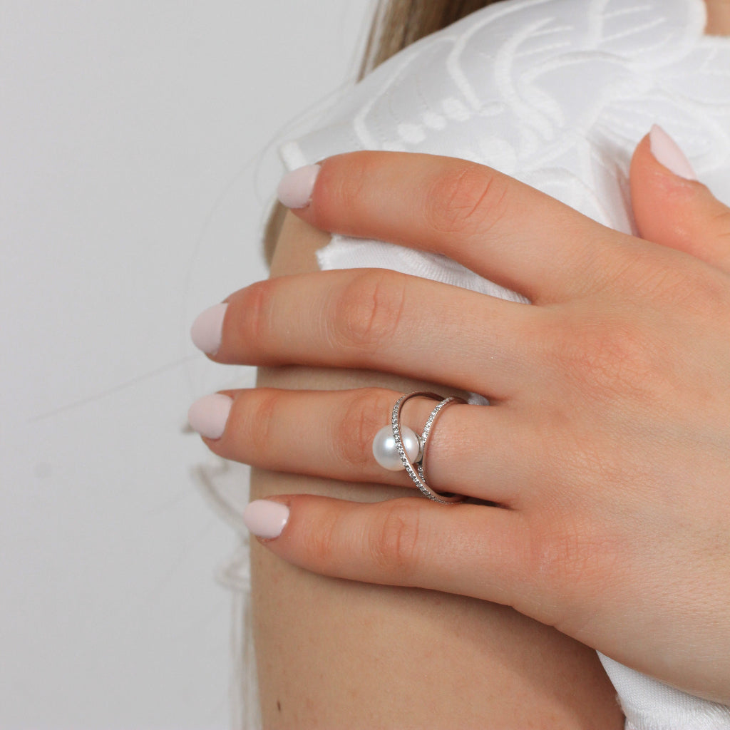 Sortija en oro blanco de 18 quilates de dos bandas con diamantes y una perla central. Joyería Pamplona.