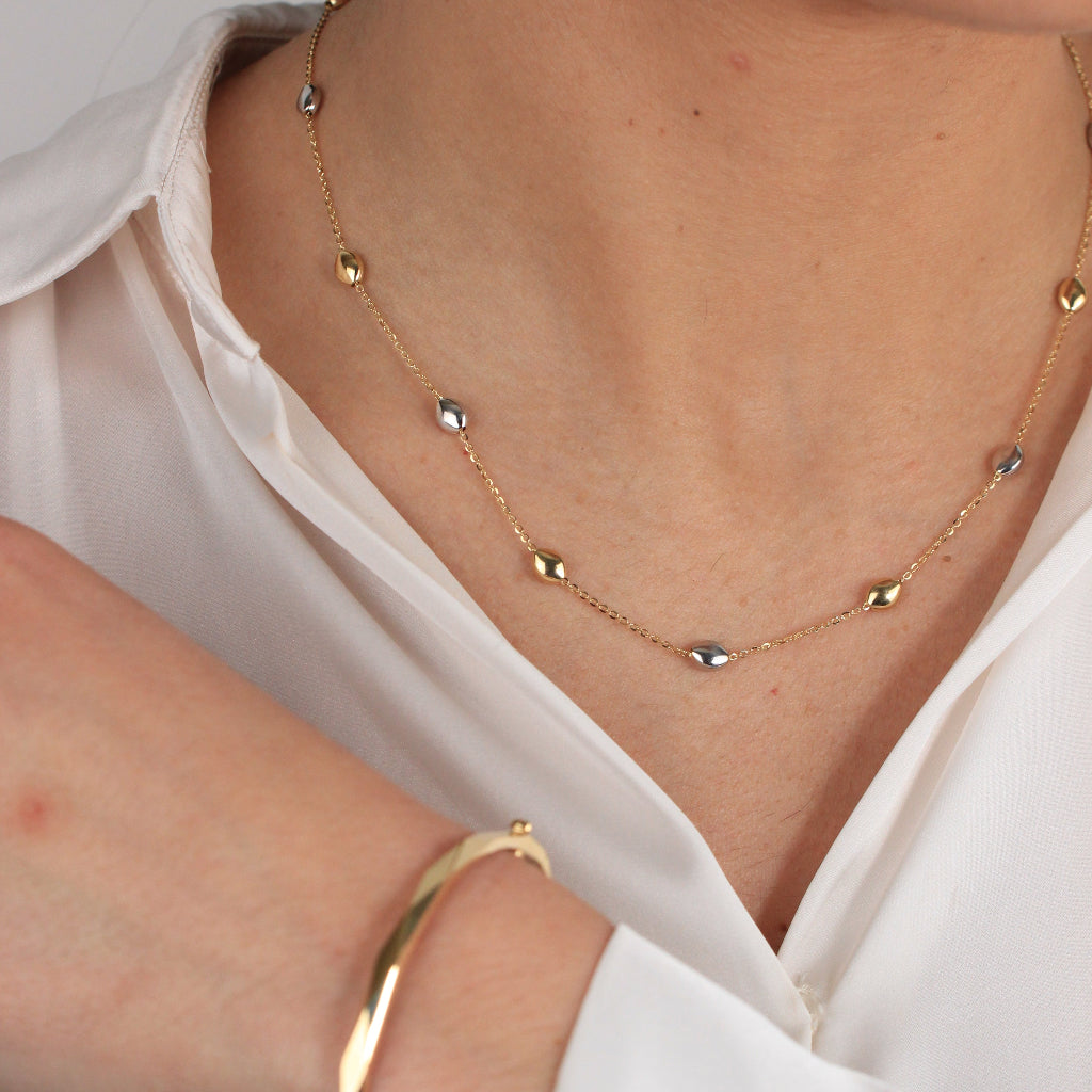 Gargantilla bicolor realizada en oro amarillo y blanco de 18 con una cadena forzada y motivos en forma de pepitas.