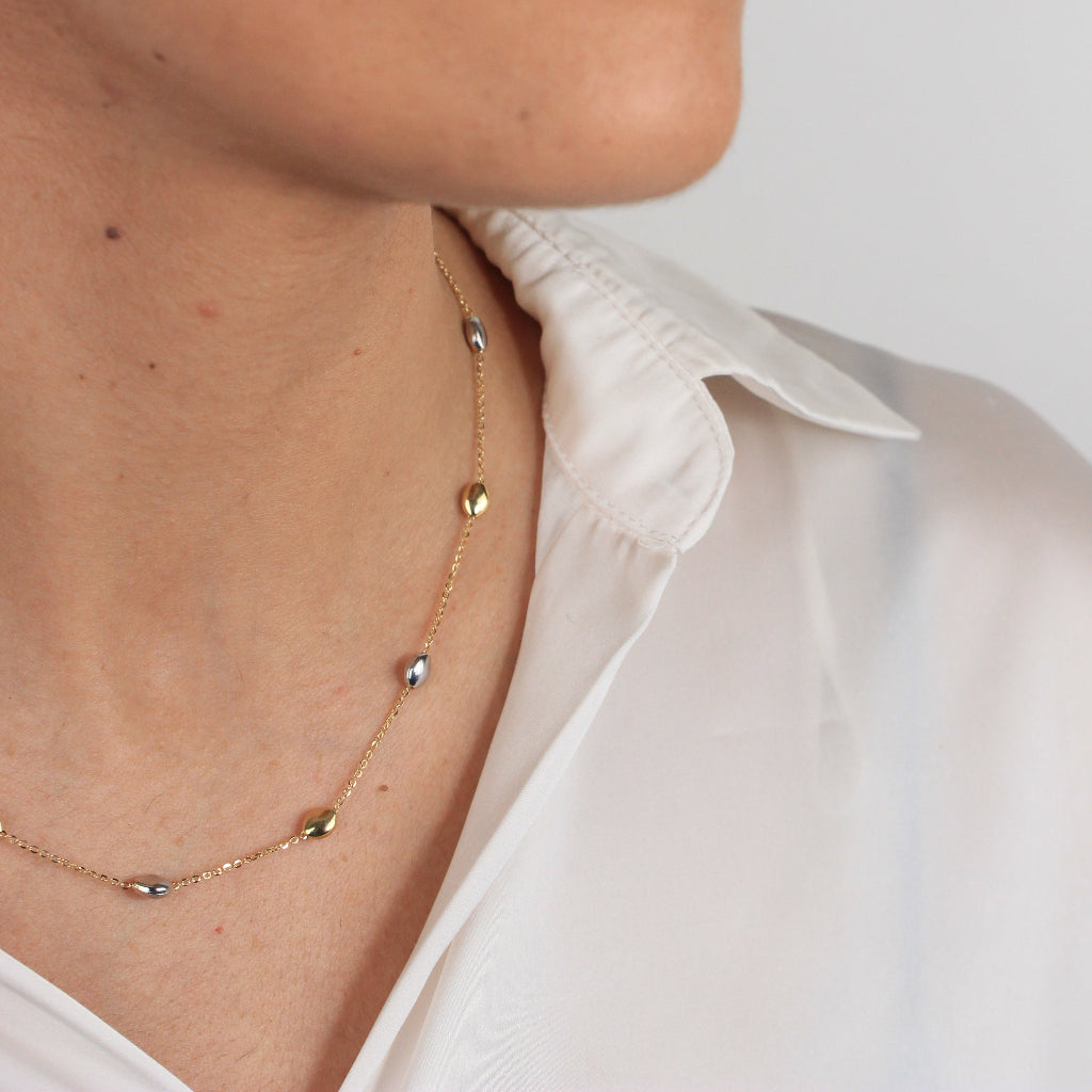 Gargantilla bicolor realizada en oro amarillo y blanco de 18 con una cadena forzada y motivos en forma de pepitas.