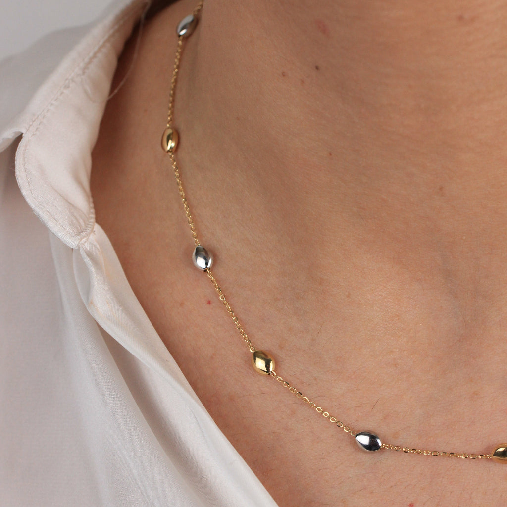 Gargantilla bicolor realizada en oro amarillo y blanco de 18 con una cadena forzada y motivos en forma de pepitas.