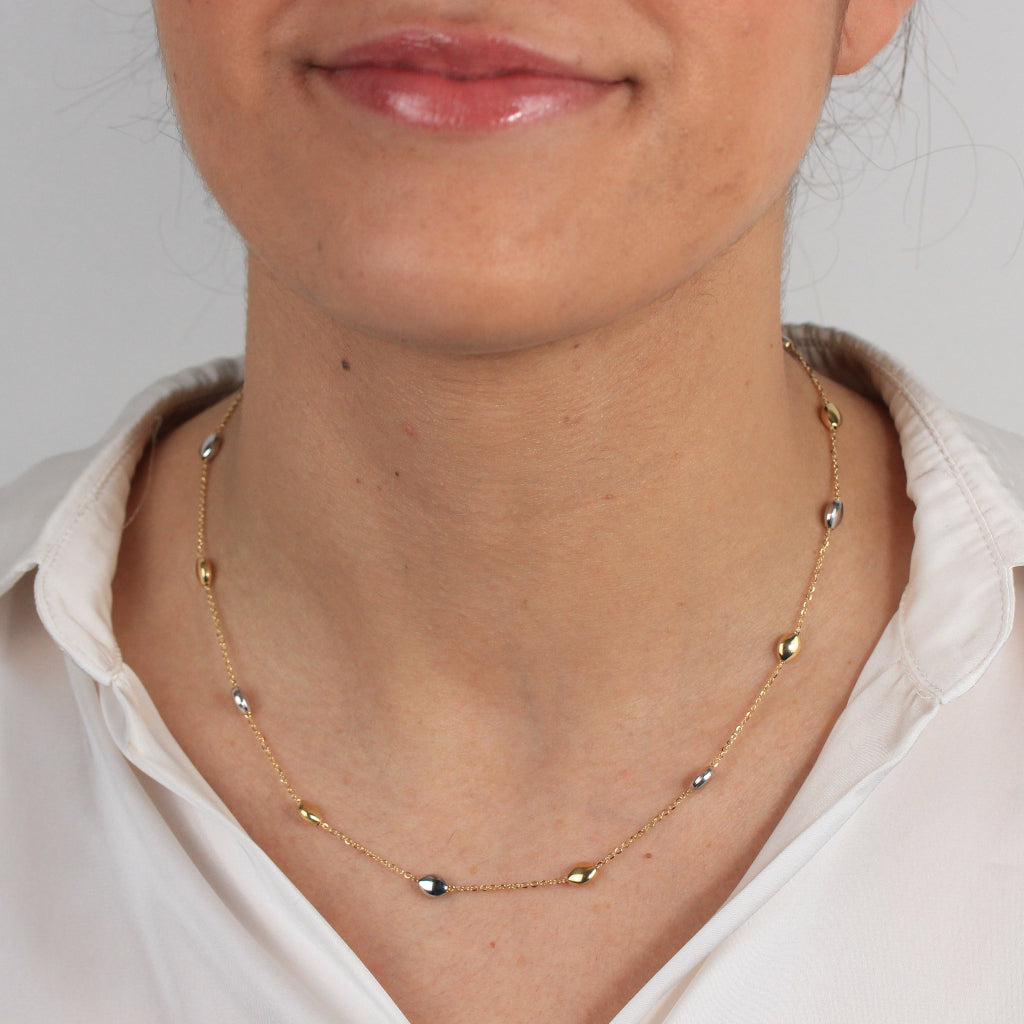 Gargantilla bicolor realizada en oro amarillo y blanco de 18 con una cadena forzada y motivos en forma de pepitas.