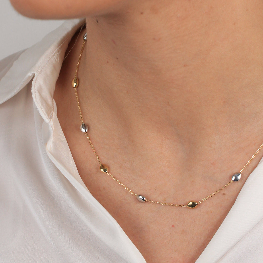 Gargantilla bicolor realizada en oro amarillo y blanco de 18 con una cadena forzada y motivos en forma de pepitas.