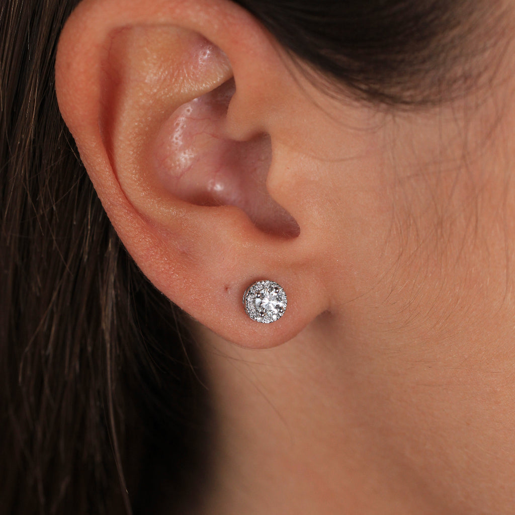 Pendientes de oro blanco de 18k con un diamante solitario y orla de diamantes