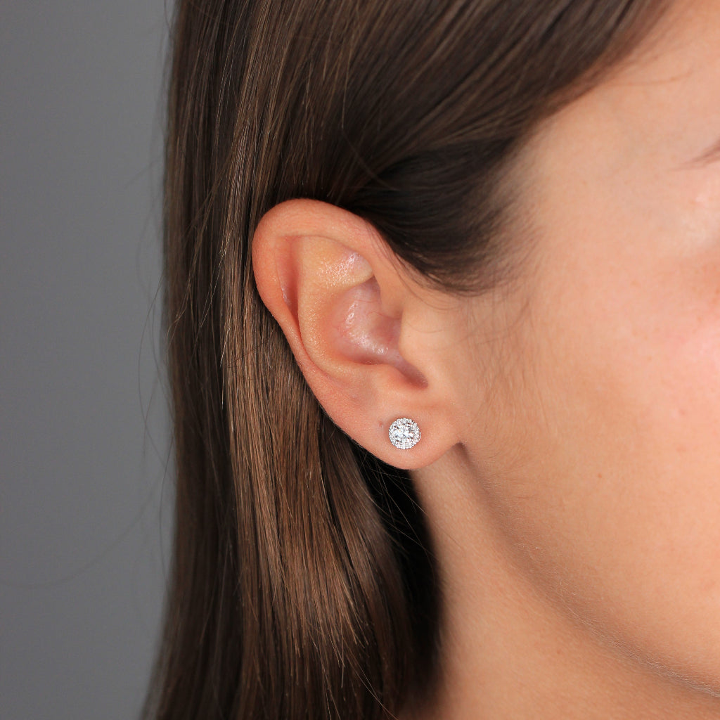 Pendientes de oro blanco de 18k con un diamante central y una orla de diamantes