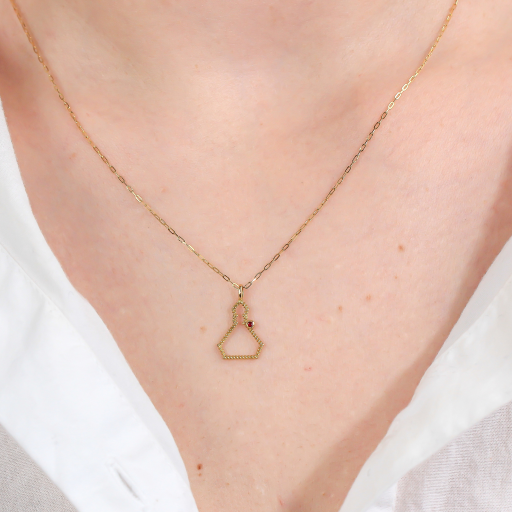 Collar realizado en oro amarillo de 18 quilates con la silueta de San Fermín en hilo trenzado y un rubí