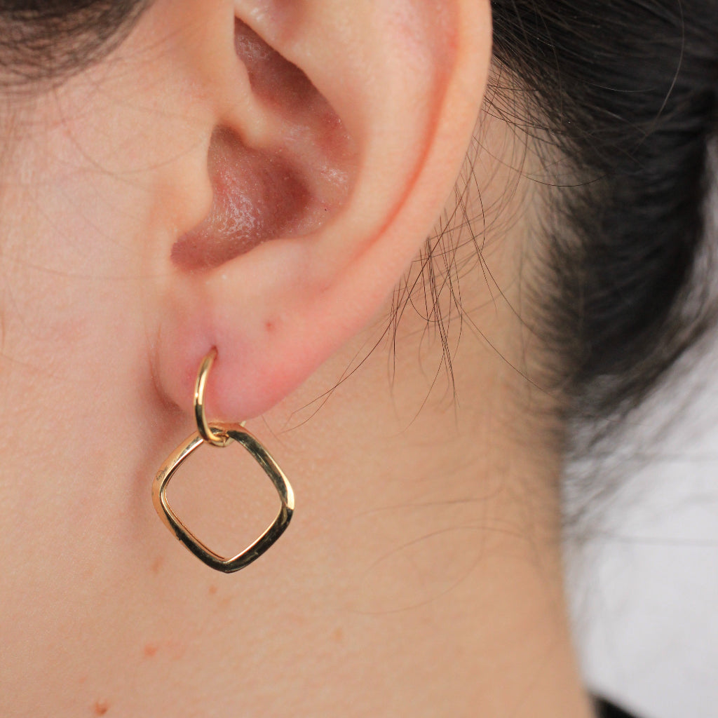 Pendientes de aro en oro amarillo de 18 quilates con un colgante abierto cuadrado suavizado.