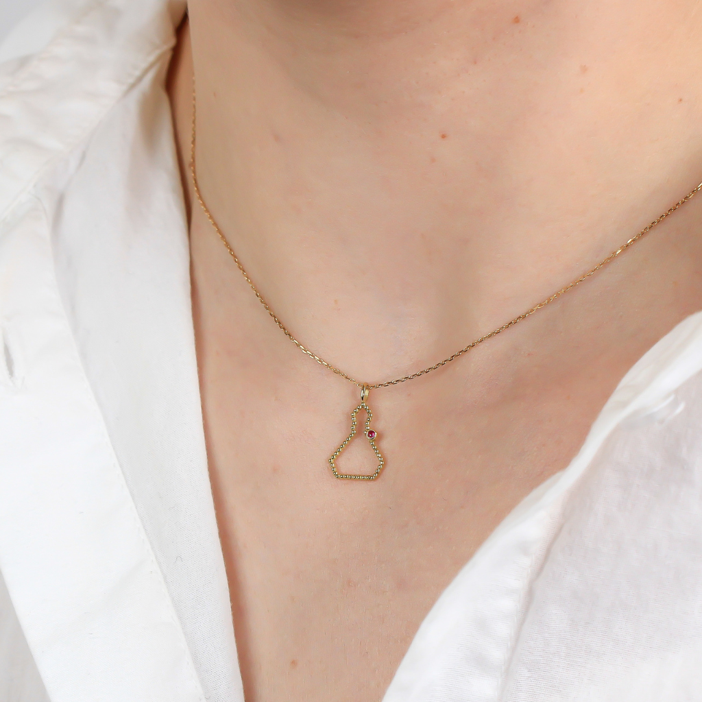 Collar realizado en oro amarillo de 18 quilates con la silueta de San Fermín en hilo de bolitas y un rubí