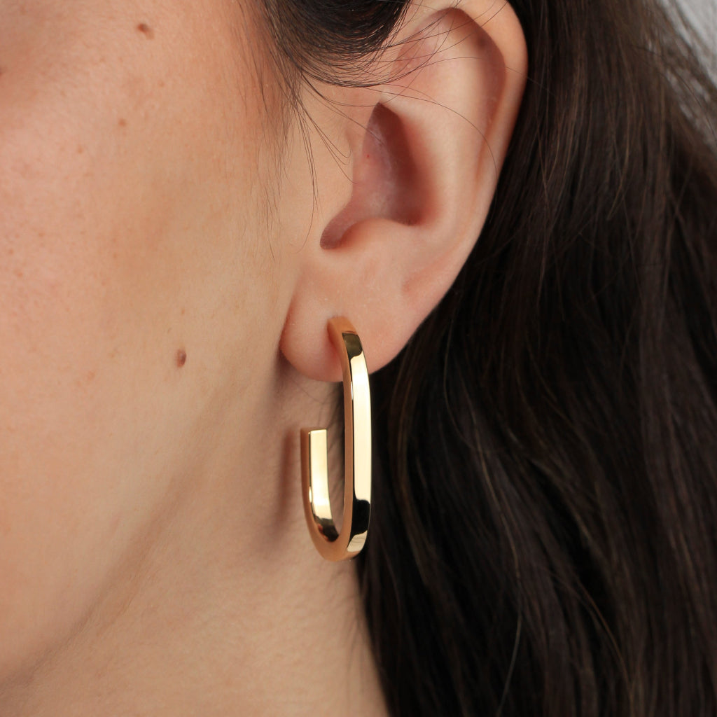 Pendientes estilo aro realizados en oro amarillo de 18 quilates con forma redonda alargada.