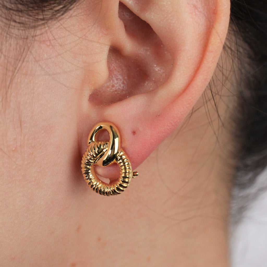 Pendientes en oro amarillo de 18 quilates con dos aros enlazados en forma de ocho. El aro inferior está facetado. Sistema de cierre omega.