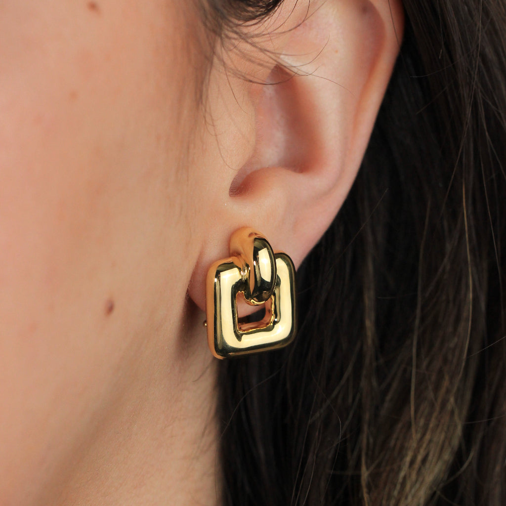 Pendientes en oro amarillo de 18 quilates en forma de cuadrado suavizados con un aro en la parte superior. Sistema de cierre omega.