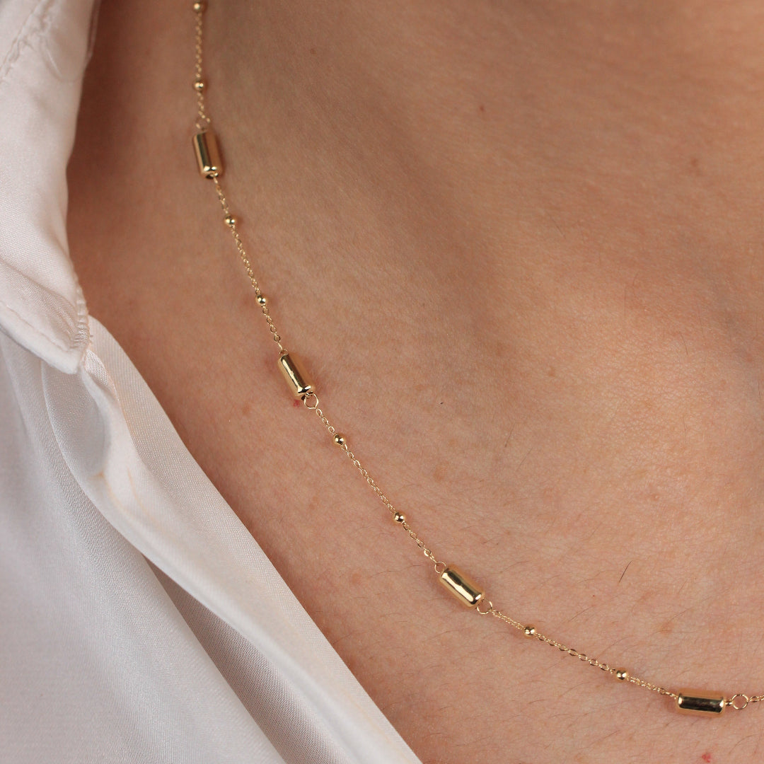 Gargantilla en oro amarillo de 18 quilates con motivos de tubos y bolas pequeñas.