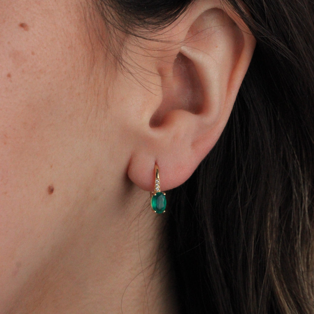 Pendientes en oro amarillo de 18 quilates con una esmeralda talla oval en garras y tres circonitas.