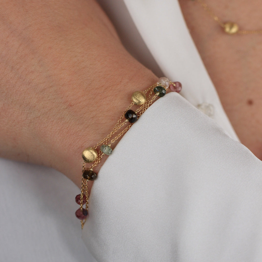 Pulsera realizada en oro amarillo de 18 quilates con tres cadenas, motivos circulares mate, turmalinas y cuarzo fumé.