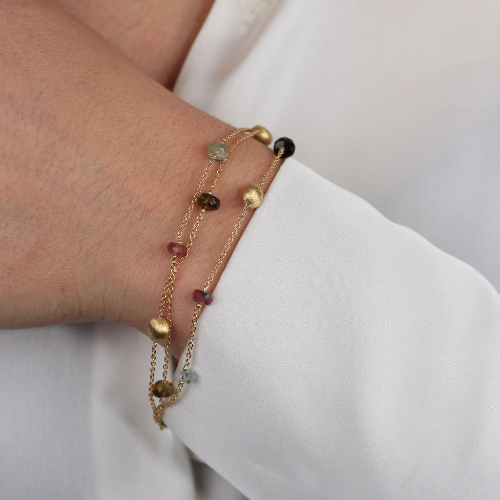 Pulsera realizada en oro amarillo de 18 quilates con tres cadenas, motivos circulares mate, turmalinas y cuarzo fumé.