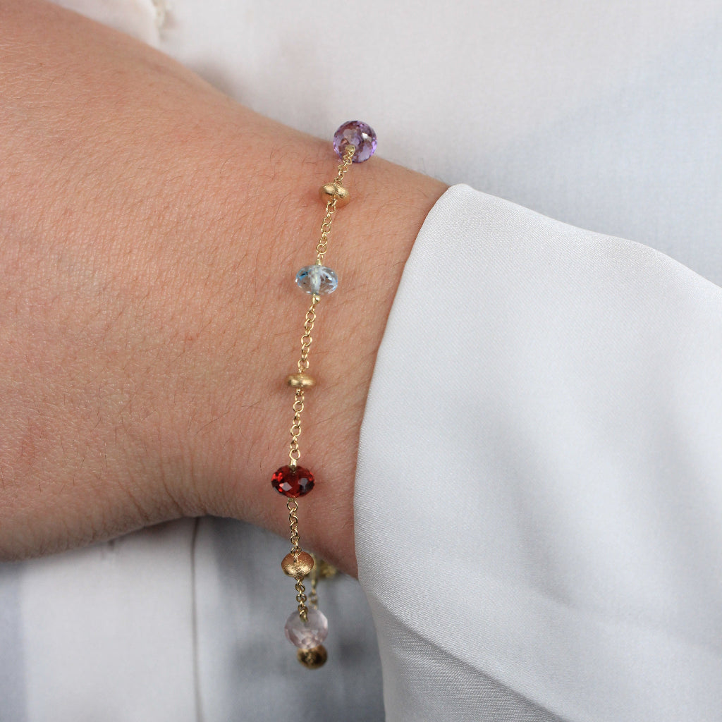 Pulsera realizada en oro amarillo de 18 quilates con motivos de oro y piedra natural de varios colores.