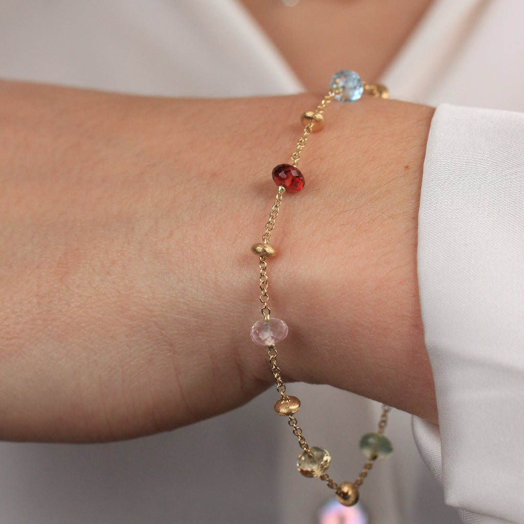 Pulsera realizada en oro amarillo de 18 quilates con motivos de oro y piedra natural de varios colores.