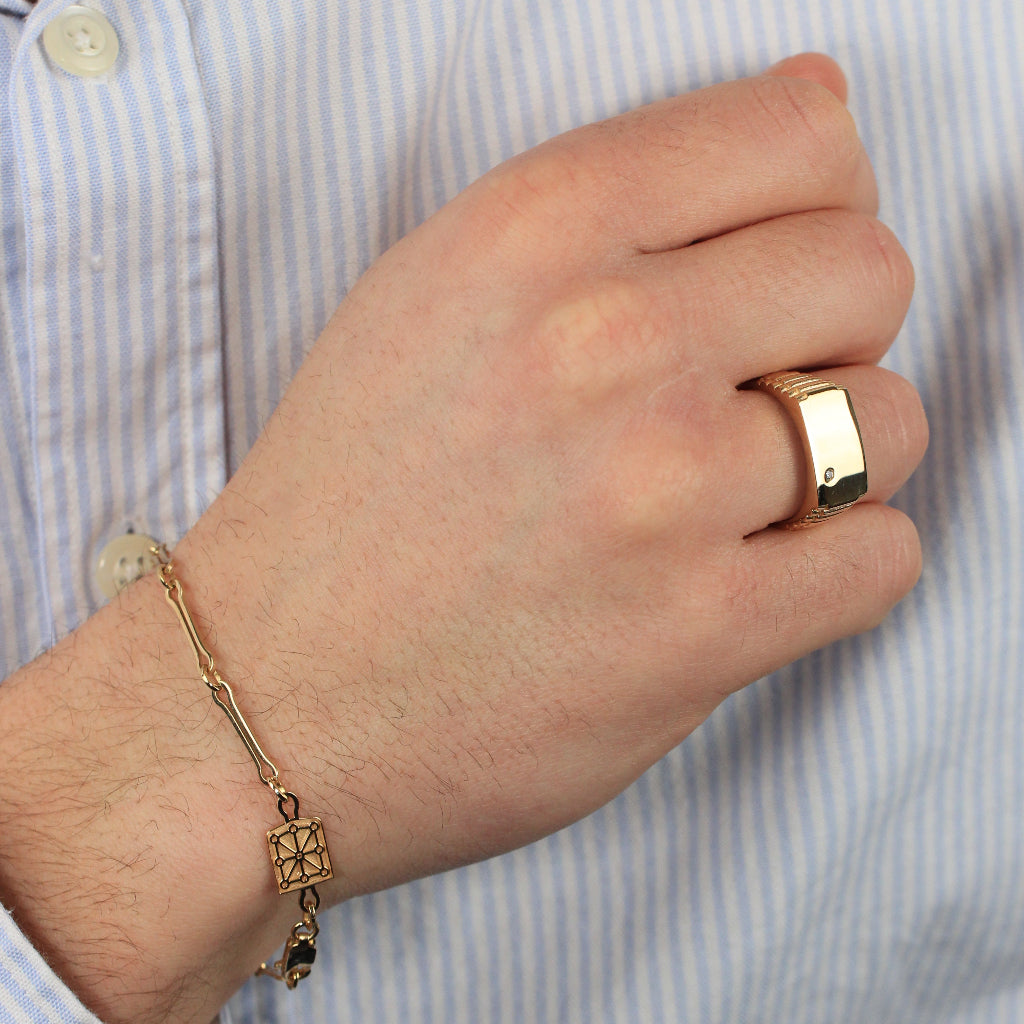 Sello rectángular con una circonita y brazo texturizado. Realizado en oro amarillo de 18 quilates.