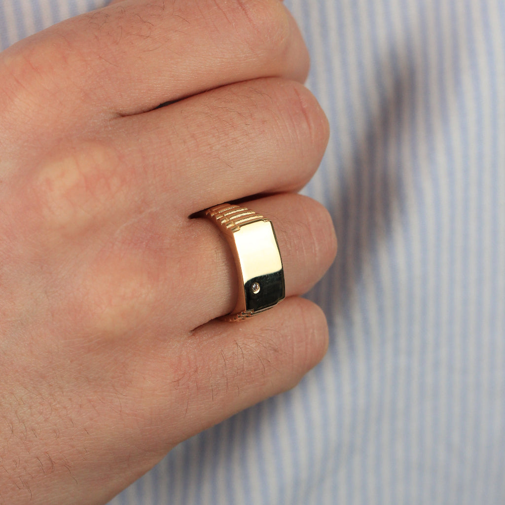 Sello rectángular con una circonita y brazo texturizado. Realizado en oro amarillo de 18 quilates.