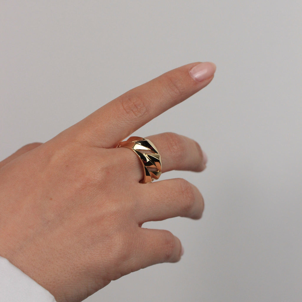 Sortija realizad en oro amarillo de 18 quilates con un diseño poligonal en relieve con huecos. El ancho del anillo es de 10mm.