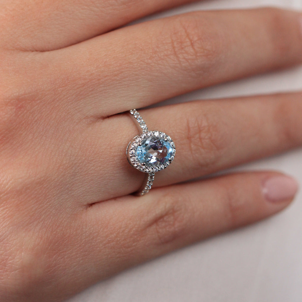 Sortija realizada en oro blanco de 18 quilates con una aguamarina central, orla de circonitas y circonitas en el brazo.