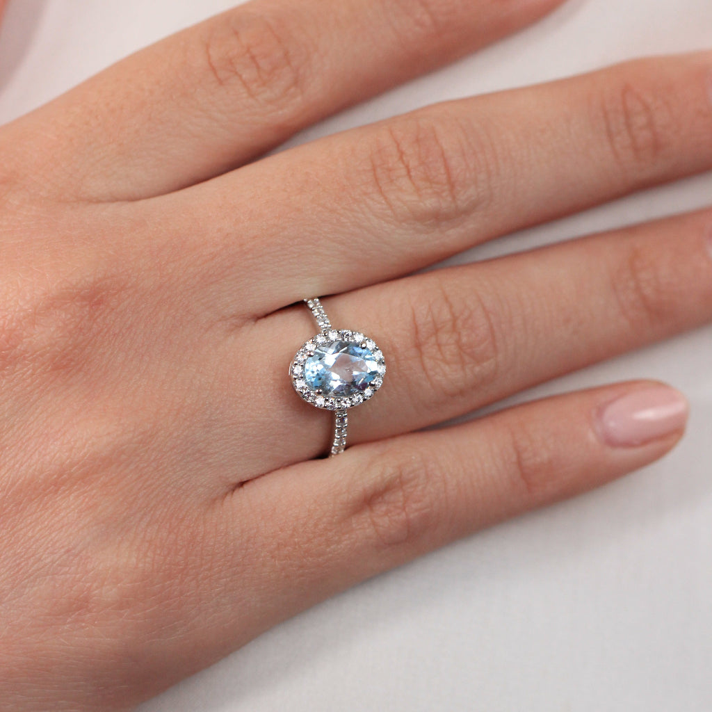 Sortija realizada en oro blanco de 18 quilates con una aguamarina central, orla de circonitas y circonitas en el brazo.