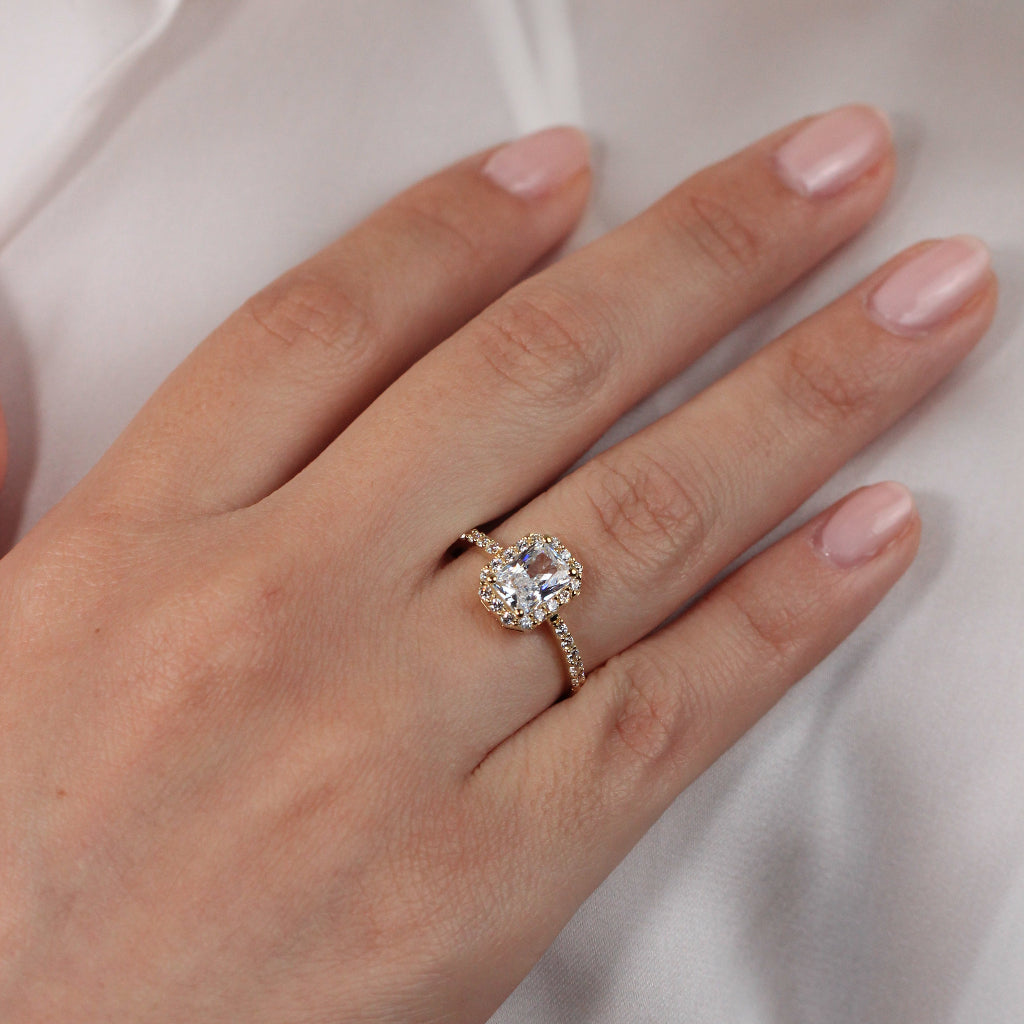 Sortija realizada en oro amarillo de 18 quilates con una circonita central, orla de circonitas y circonitas en los brazos.