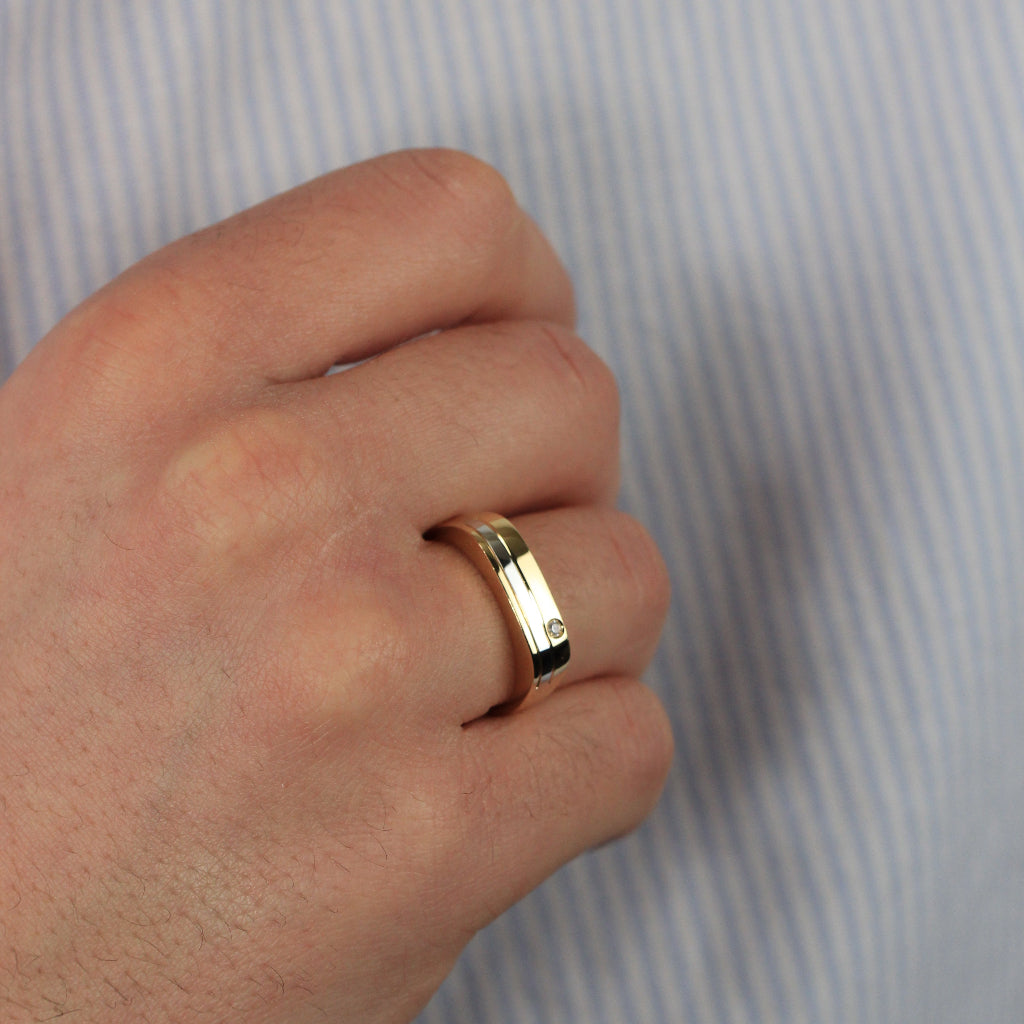 Sortija bicolor realizada en oro amarillo y blanco de 18 quilates con una banda central y una circonita engastada. El anillo tiene un ancho de 5,2mm.