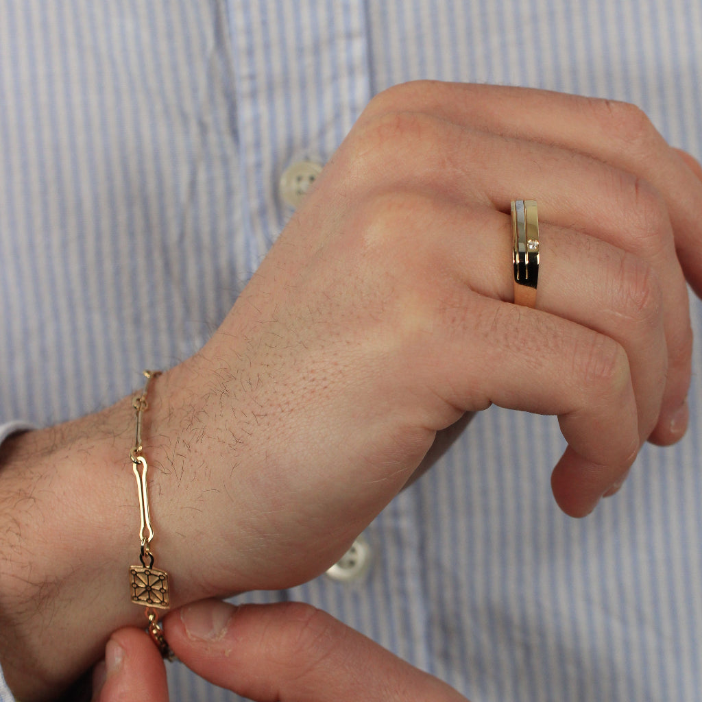 Sortija bicolor realizada en oro amarillo y blanco de 18 quilates con una banda central y una circonita engastada. El anillo tiene un ancho de 5,2mm.