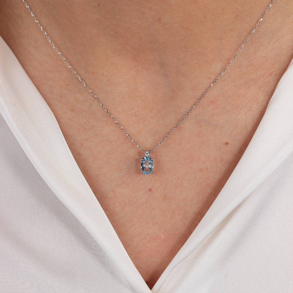 Collar en oro blanco de 18 quilates con un colgante de topacio azul talla oval en garras y una circonita.