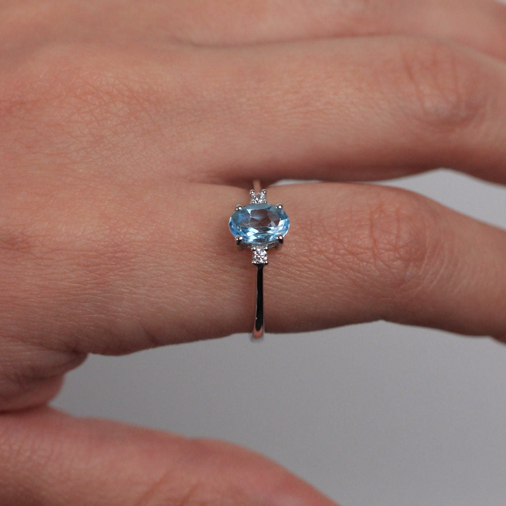 Sortija realizada en oro blanco de 18 quilates con un topacio azul central y dos circonitas.