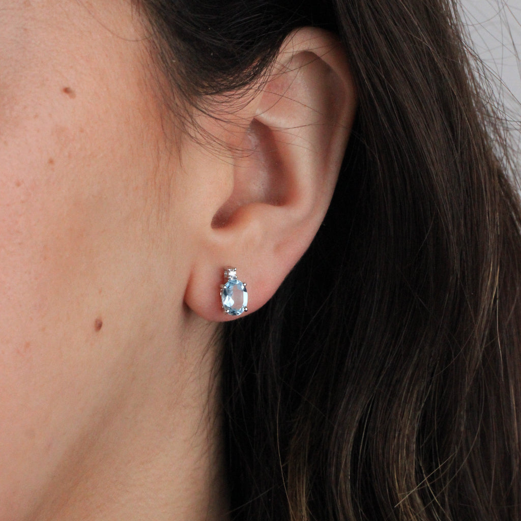 Pendientes tu y yo de oro blanco de 18 quilates con un topacio azul talla oval en garras y una circonita.