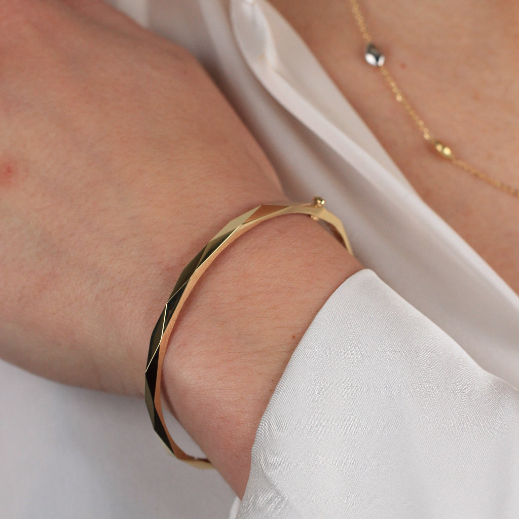 Pulsera rígida esclava realizada en oro amarillo de 18 quilates facetada en rombos.