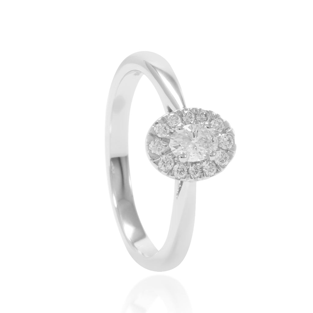 Sortija de oro blanco de 18 quilates con un diamante central talla oval de 0,21cts. y una orla de 12 diamantes talla brillante. Joyería Pamplona.